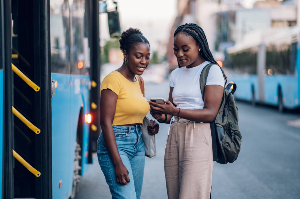 des filles qui regardent le budget des bus pour un voyage en Martinique sur leur téléphone